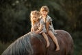 Little sisters outdoor riding on chestnut horse