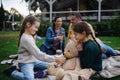 Little sisters sitting on blanket and playing with teddy bear on picnic with parents outdoor in park Royalty Free Stock Photo