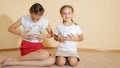 Little sisters sitting on floor and paint a t-shirt with their hands Royalty Free Stock Photo