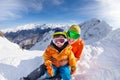 Little skier, father sit in snow on mountain peak Royalty Free Stock Photo