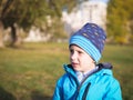 Little Slavic boy child portrait in spring or autumn on the lawn in a city park