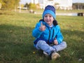 Little Slavic boy child portrait in spring or autumn on the lawn in a city park