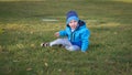 Little Slavic boy child portrait in spring or autumn on the lawn in a city park