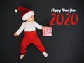 Little sleeping boy dressed as Santa Claus with a gift in his hands with the text Happy New Year 2020 Royalty Free Stock Photo