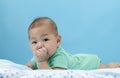 Asian baby laying on bed with his finger in mouth Royalty Free Stock Photo