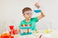 Little smart boy in safety goggles doing chemical experiments in laboratory Royalty Free Stock Photo