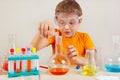 Little smart scientist in safety glasses doing chemical experiments in laboratory