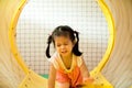 A little smile girl is crawling out of yellow tunnel at playground