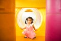 A little smile girl is crawling out of yellow tunnel at playground