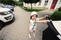 Little smiled girl with baby carriage walking in pavement at street