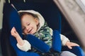 Little smiling baby child fastened with security belt in safety car seat. Royalty Free Stock Photo