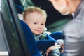 Little smiling baby child fastened with security belt in safety car seat. Royalty Free Stock Photo