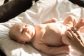 A little smiling baby lying on a bed on white sheets Royalty Free Stock Photo