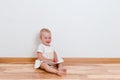 Little smiling barefoot baby girl sits on the floor