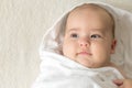 Little smiling beautiful newborn baby child lying on his back on bed after shower wrapped in white warm soft Royalty Free Stock Photo