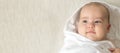 Little smiling beautiful newborn baby child lying on his back on bed after shower wrapped in white warm soft diaper towel - Royalty Free Stock Photo