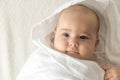 Little smiling beautiful newborn baby child lying on his back on bed after shower wrapped in white warm soft Royalty Free Stock Photo