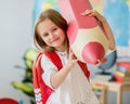 Little smiling blond girl holding huge red pencil in the school classroom Royalty Free Stock Photo