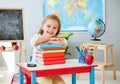 Little smiling blond girl holding hands on the books in the school classroom