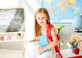 Little smiling blond girl standing in the school classroom