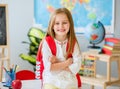 Little smiling blond girl standing in the school class