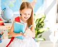 Little smiling blond girl standing in the school classroom