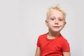 Little smiling blonde boy in red t-shirt. Portrait. Space for text. White background