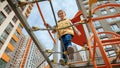 Little smiling boy crossing rope bridge between two towers on outdoor kids playground Royalty Free Stock Photo