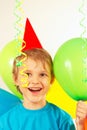 Little smiling boy in holiday hat with festive balls and streamer Royalty Free Stock Photo