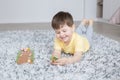 Little smiling boy lies on carpet and plays plays board game with wooden rabbits and carrots Royalty Free Stock Photo