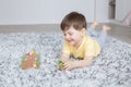 Little smiling boy lies on carpet and plays plays board game with wooden rabbits and carrots Royalty Free Stock Photo