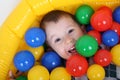 Little smiling boy playing in colorful balls playground