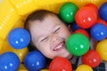 Little smiling boy playing in colorful balls playground