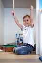 Little smiling boy is playing on a floor at home in billiards