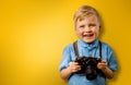 Little smiling boy with retro camera on a yellow background with copy space. child photographer Royalty Free Stock Photo
