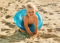 Little smiling boy sits in lifebuoy on beach Royalty Free Stock Photo