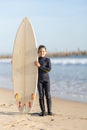 A little smiling boy standing on the seashore with a big surfing board Royalty Free Stock Photo