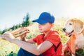 Little smiling boy weared baseball cap with a huge baguette sandwich with his beagle dog friend during a mountain hiking resting Royalty Free Stock Photo