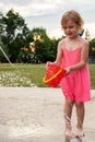 Little smiling child playing at water splash pad fountain in the park playground during hot summer day Royalty Free Stock Photo