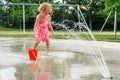 Little smiling child playing at water splash pad fountain in the park playground during hot summer day Royalty Free Stock Photo