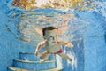 Little smiling child swimming underwater in pool