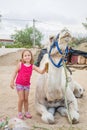 Little smiling girl brushing dromedary sitting in countryside on summer Royalty Free Stock Photo
