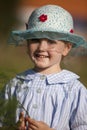 A little smiling girl in a blue hat and a country dress Royalty Free Stock Photo