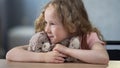 Little smiling girl hugging favorite teddy bear sitting at table happy childhood Royalty Free Stock Photo