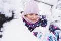 Little smiling girl kid walking in beautiful winter forest park among trees branches covered with snow. Pink hat scarf snood Royalty Free Stock Photo