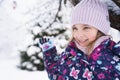 Little smiling girl kid walking in beautiful winter forest park among trees branches covered with snow. Pink hat scarf snood Royalty Free Stock Photo