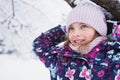 Little smiling girl, kid walking in beautiful winter forest, park among trees, branches covered with snow. Pink hat, scarf, snood Royalty Free Stock Photo