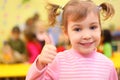 Little smiling girl in kindergarten shows ok