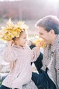 Little smiling girl looks at her dad sitting on a stone in a wreath of autumn leaves Royalty Free Stock Photo