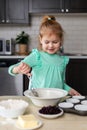 Little smiling girl making dough in kitchen. Small happy child cooking. Kid making homemade muffins